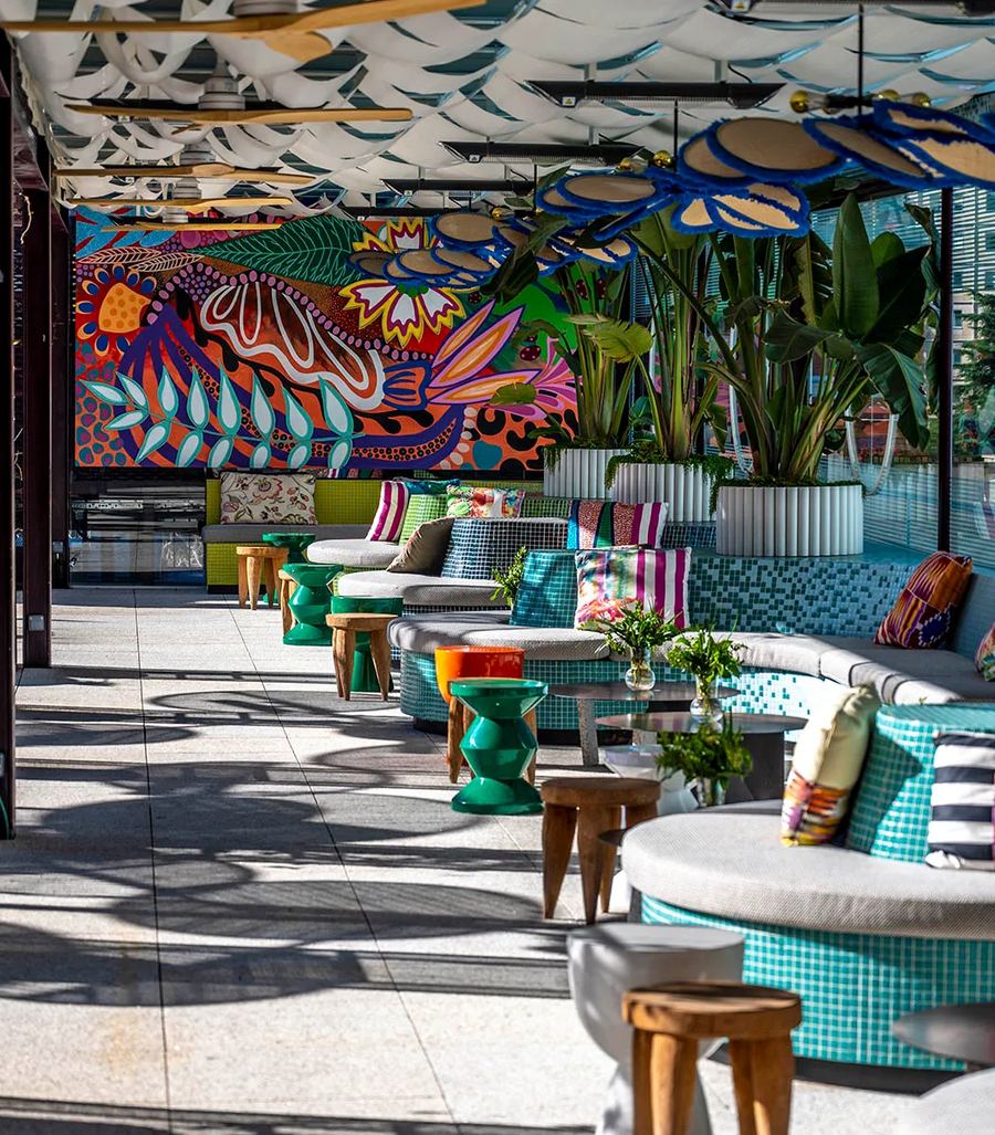 Interior con mural artístico, plantas y mobiliario de diseño