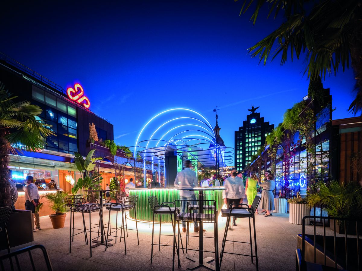 La terraza The Roof a la hora azul, con el bar iluminado, palmeras, el rótulo de neón de ABC y el skyline de Madrid al fondo