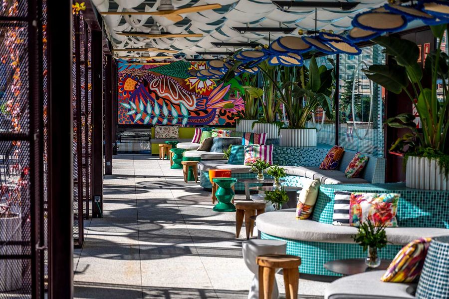 Zona lounge de la terraza con sofás, cojines de colores y mural artístico